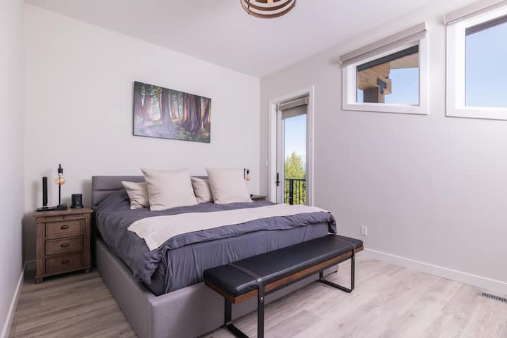 The main floor bedroom offers a peaceful retreat with a plush king bed, direct access to the front deck, a spacious closet, and a private full bathroom featuring a walk-in shower—perfect for comfort and convenience during your stay.