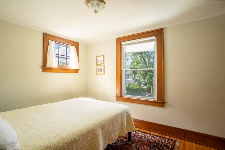 房子前面的第二间卧室配有双人床，宽敞的衣柜配有全身镜、行李架、床头柜、灯具、地毯。   