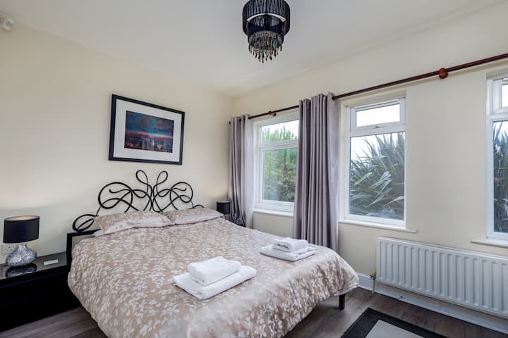 غرفة نوم مزدوجة في الطابق الأرضي (غرفة الاستحمام عبر القاعة مباشرة من غرفة النوم هذه) مع سرير بحجم كبير.