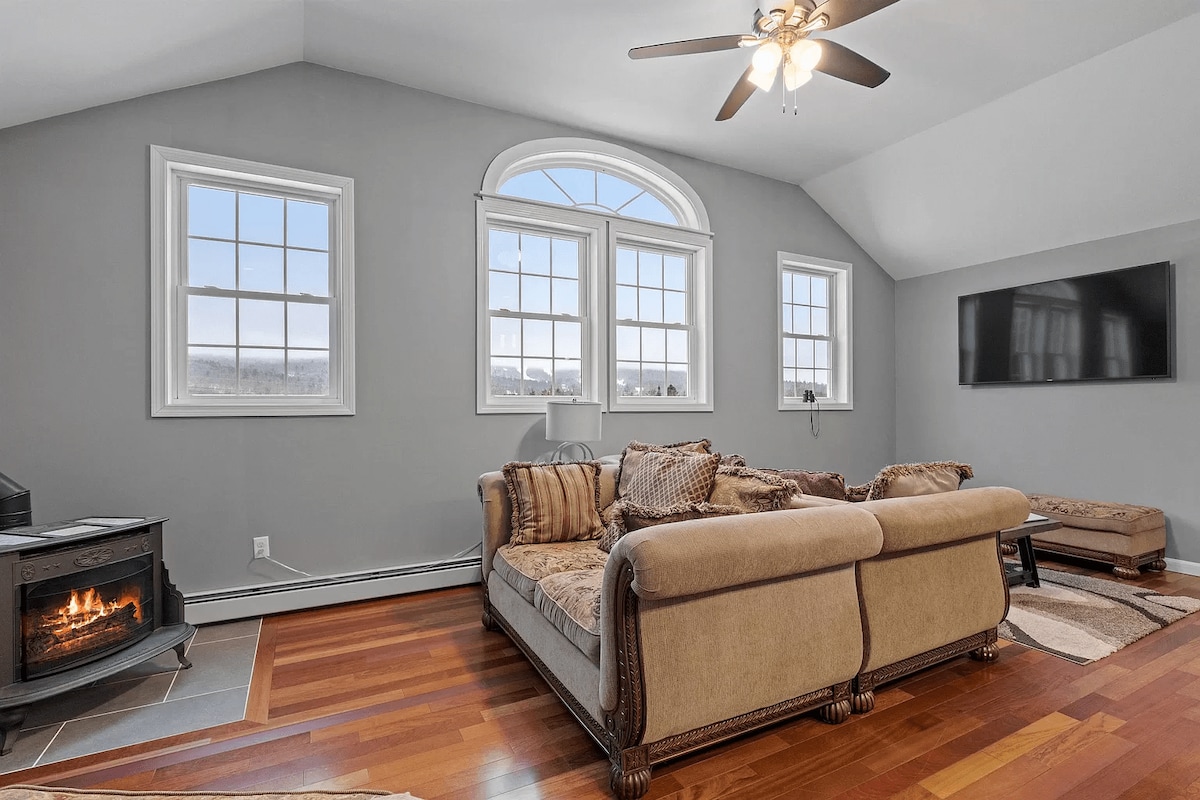 Furahia sebule yenye starehe iliyo na meko ya gesi, inayofaa kwa ajili ya kupumzika jioni. Madirisha makubwa hutoa mandhari ya ajabu ya milima, na kuleta mazingira ya asili ndani ya nyumba. Ukiwa na televisheni ya inchi 65 na viti vya starehe, ni sehemu nzuri ya kupumzika na kufurahia ukaaji wako.