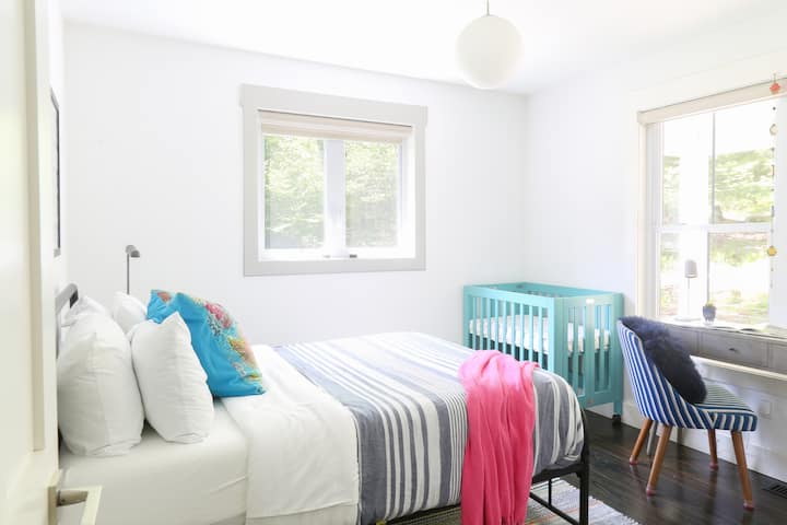 Balancing work and baby in perfect harmony within our bedroom sanctuary. Designed for families traveling with little ones, this room includes a colorful crib, cozy full bed, and enough natural light to brighten any morning.