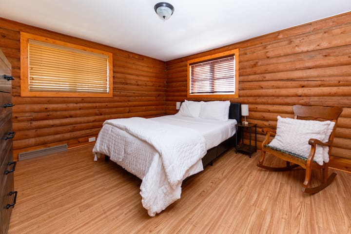 The second bedroom includes a queen-sized bed, a spacious dresser, and a cozy rocking chair perfect for relaxing or a spot for grandma to unwind!