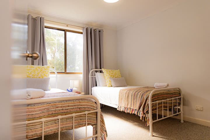 "Koodjinok Room" named for the dancing Grey Fantails. Peaceful dual singles, upstairs looking out onto the woodland and granite boulders. Comfortable European topped mattresses, generous built in robes, bedside table and lamp.
