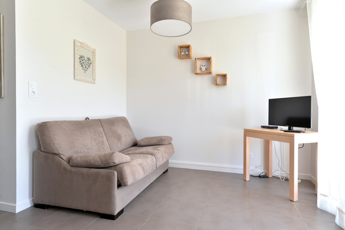 Moderný obývací priestor s pohodlnou rozkladacou pohovkou, ktorý sa otvára na súkromnú terasu. Svetlý a prívetivý priestor, ideálny na relaxáciu alebo vychutnávanie si prírody v pokoji.