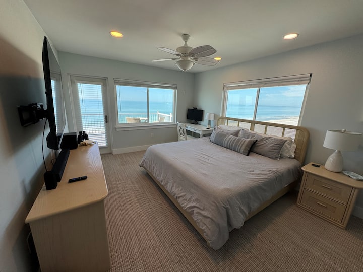 Master bedroom with king bed, private bathroom, office area, tv and access to balcony overlooking the beach.