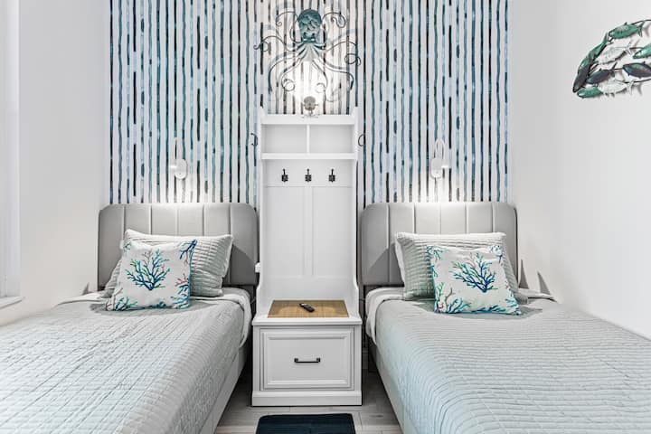 NIEUWE Tweepersoonskamer met 2 bedden comfortabel voor volwassenen en kinderen.  Beperkte ruimte.  Kleine kledingkast/nachtkastje voor je onmiddellijke behoeften.  Opties om een kleine koffer onder de bedden te bewaren.  Individuele leeslampjes met USB-adapters.