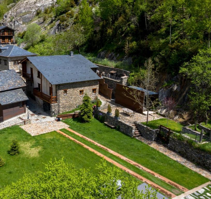 A spacious outdoor area features well-maintained lawns and pathways leading to various sections of the property. The landscape includes a mixture of greenery and stone paths, bordered by rustic stone walls and trees, providing a peaceful, natural setting.