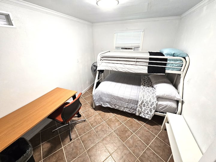 Chambre n °5 au rez-de-chaussée avec lits jumeaux superposés, table de bureau et chaise, table d'appoint.