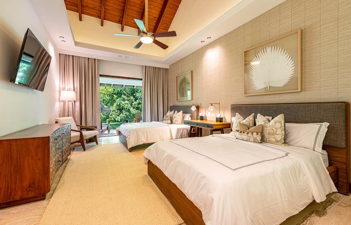 Second bedroom with 2 queen beds, en suite full bathroom, split unit AC, and patio with outside seating