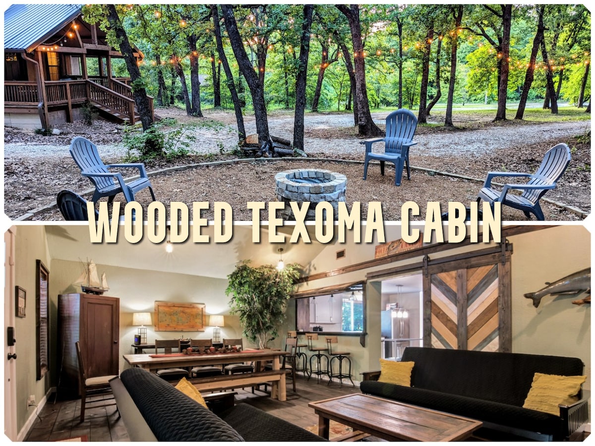 An outdoor seating area features several blue chairs arranged around a fire pit, set amidst a natural landscape of trees and gravel. The cabin's porch is visible in the background, blending into the wooded surroundings.