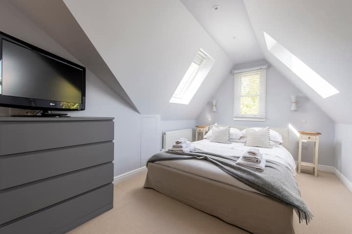Dormitorio 'The Loft' con cama tamaño queen de lujo, TV (esta es más antigua, no inteligente) y almacenamiento de ropa
