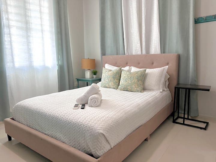 Enjoy your air-conditioned bedroom with a spacious queen bed, stylish decor, a TV, and ample closet space for a comfortable stay.
