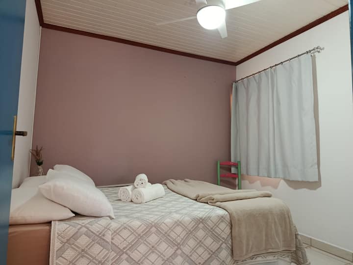 Habitación doble con ventilador de techo, cama y ropa de baño.