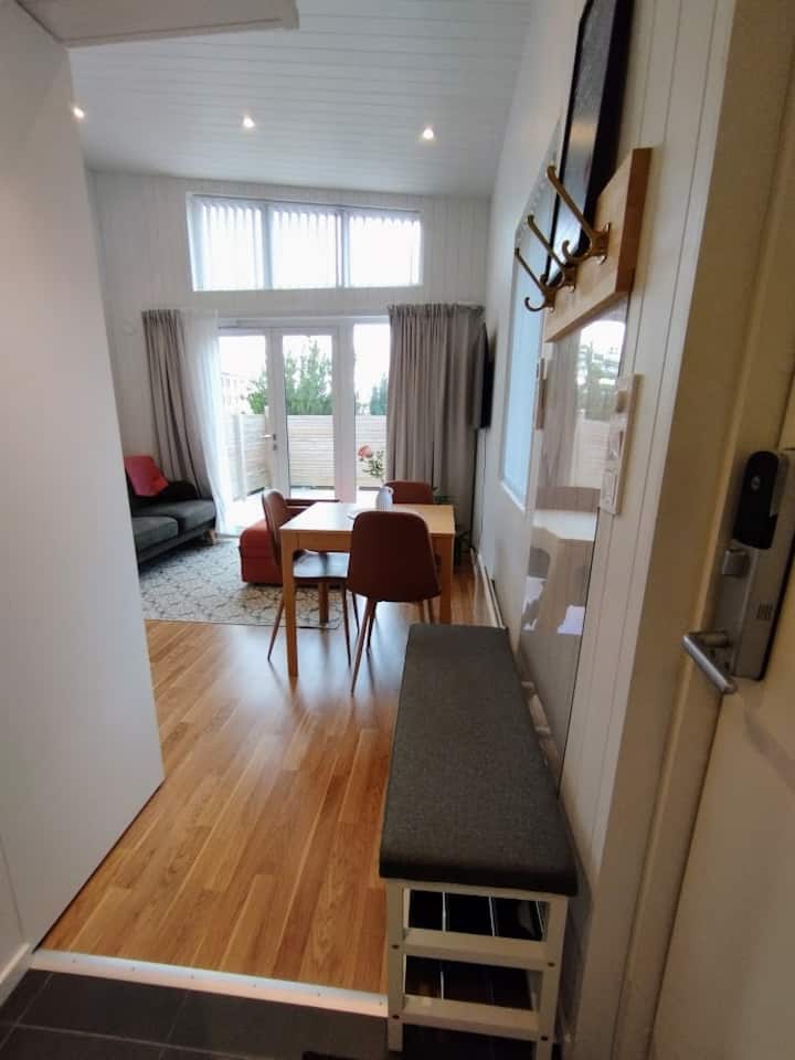 Ytterdörrens entré till höger. Utsikt över korridoren mot matsalen/köket/vardagsrummet. Bortom franska glasdörrar finns en privat veranda.