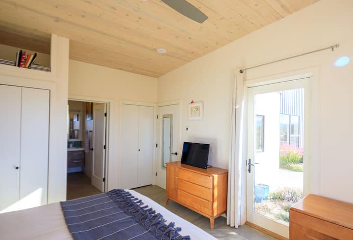 חדר שינה צמוד גדול עם מיטת קינג וגישה למרפסת.