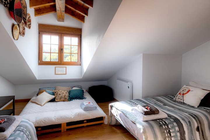 Second bedroom featuring a futon (set up as a double bed which can be split into 2 singles), 2 additional single beds, 2 small bedside tables and a baggage rack.