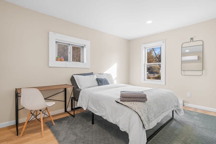 Une chambre spacieuse avec un lit queen vêtu de draps moelleux, complétée par un bureau et une chaise élégants.