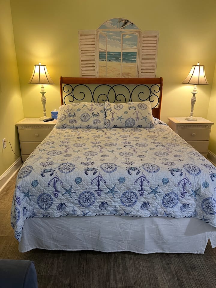 Toto je manželská posteľ veľkosti Queen. Na oboch stranách postele je stojan s lampou. 