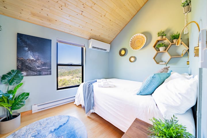 Оваа спална соба има поглед кон планината и е достапна од спиралните скали кои водат до најгорниот кат на мојата дрвена колиба.