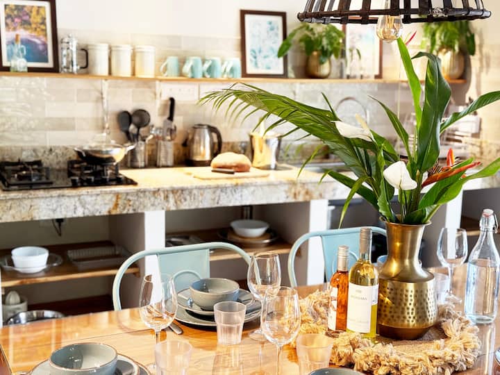 This bright and airy kitchen is fully equipped and designed for comfort and functionality. A spacious dining table invites shared meals with family and friends. Feel free to reach out regarding any further information on the kitchen set up.