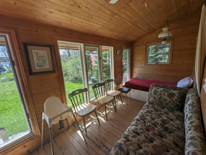 Profitez de la véranda sereine qui capte la lumière du matin, avec un lit de repos parfait pour se détendre et une vue sur le plein air.
