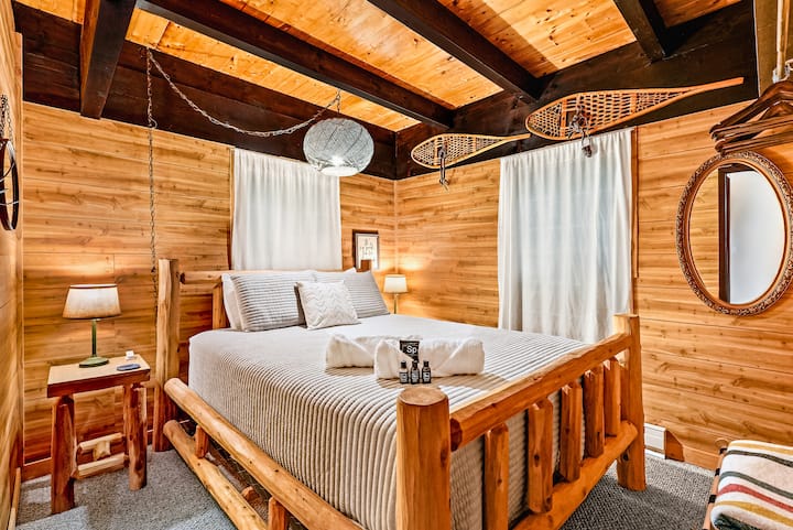 Rustic master bedroom with log-frame bed and warm cabin charm