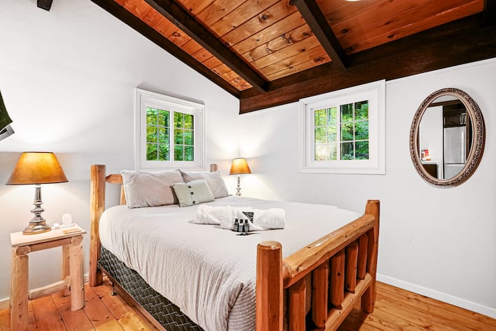 Bright guest bedroom with natural wood accents and forest views