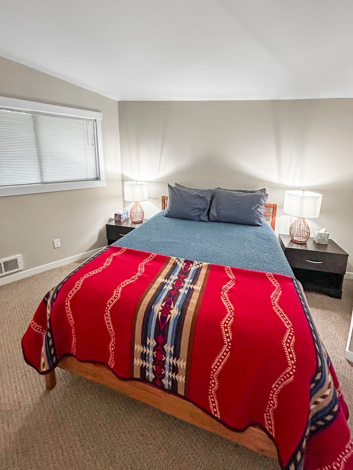 Second Bedroom with Queen Bed  – This inviting second bedroom features a queen-size bed, soft lighting, and a cozy Pendleton blanket for added warmth and style. A perfect retreat for a restful night’s sleep in a peaceful, private space.