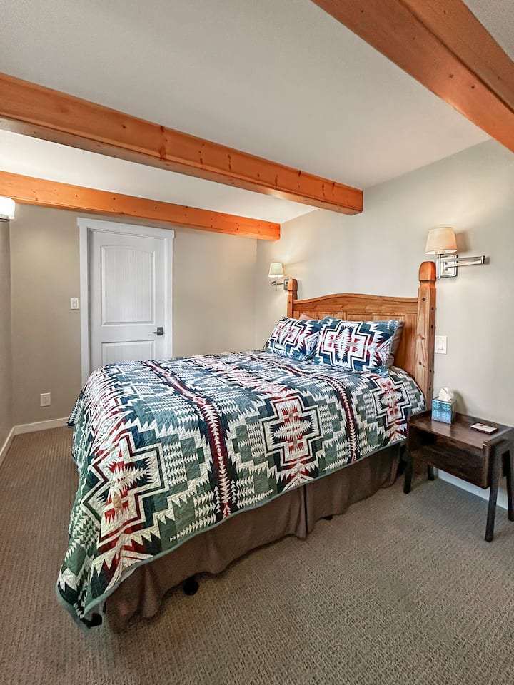 Primary Bedroom with Queen Bed & Pendleton Blankets – The primary bedroom features a comfortable queen-size bed, warm lighting, and exposed wood beams for a cozy retreat. Enjoy luxurious Pendleton blankets, adding a stylish and comfortable touch.