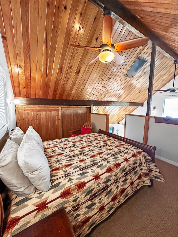 Loft Bedroom with Queen Bed  – This inviting loft bedroom features a queen-size bed with a plush down comforter and a Pendleton blanket, offering both warmth and style. A perfect retreat for a restful night’s sleep in a cozy, elevated space.