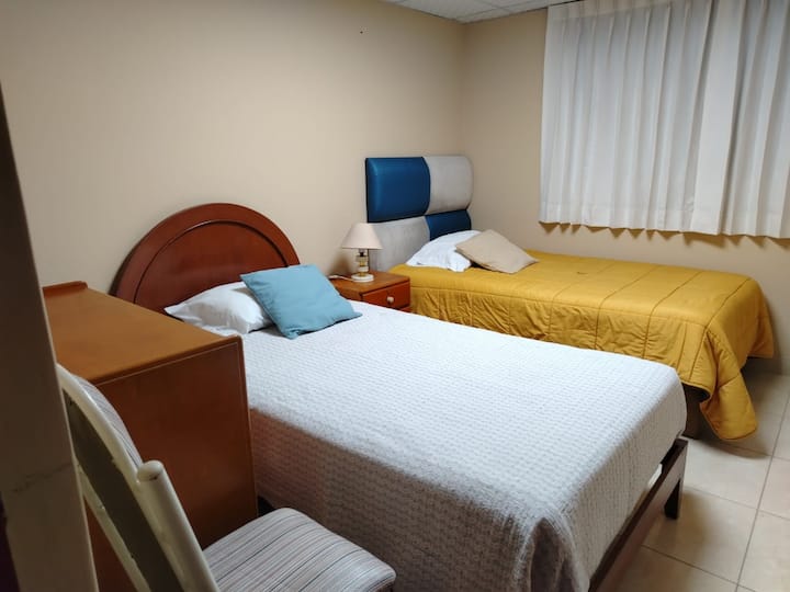 ES UNA HABITACION CON 2 CAMAS DE 1 1/2 PLAZA CADA UNA, 1 VELADOR CON LAMPARA, 1 COMODA , 1 SILLA.