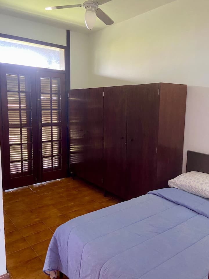 Chambre avec lit double et ventilateur de plafond. Il y a une porte de communication avec la suite, si nécessaire. Accès au balcon principal, relié à deux autres chambres et au salon, donnant sur l'entrée de la maison.