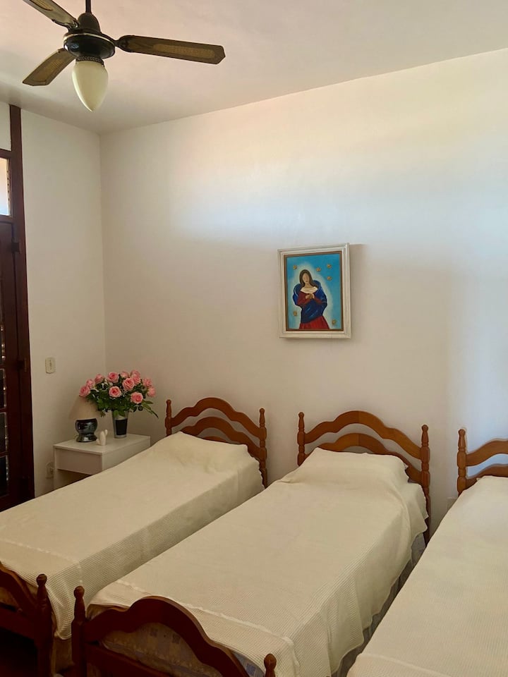 Quartier avec 3 lits simples, à côté de la salle de bain, avec ventilateurs de plafond. Il dispose d'un balcon donnant sur l'arrière, depuis le garage de la maison. Armoire avec plusieurs options de couvertures et de serviettes propres.