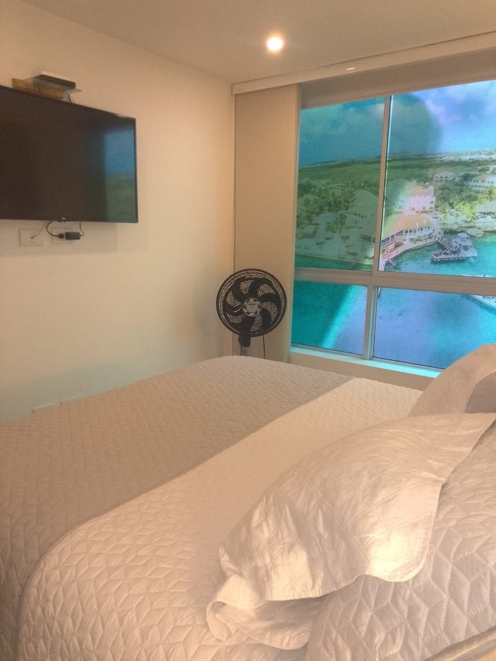 בדירה יש נוף צדדי של חדר השינה קווין,טלוויזיה, מאוורר ועט מיטה מתקפלת. 