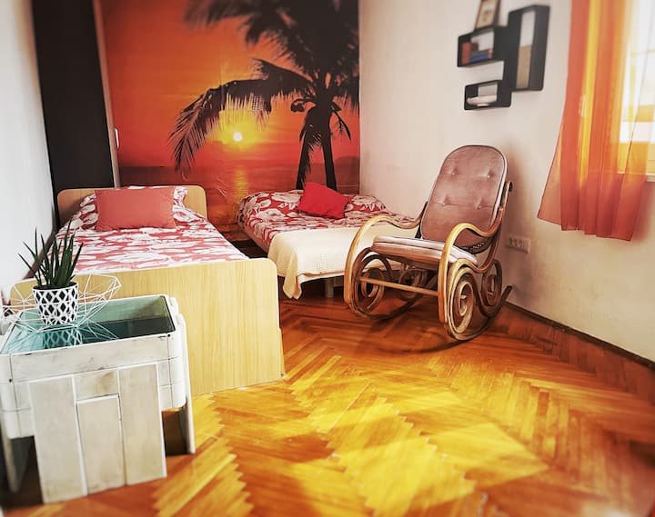 Orange and palm tree bedroom with two beds and working table. Perfect for work from home.