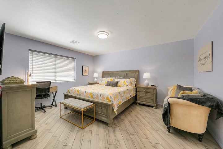 Master bedroom includes a king sized bed, couch, bathroom and small work desk.