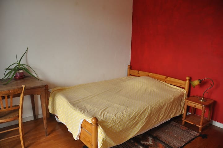 Dhomë e gjerë dhe e ndritshme, me një derë dritareje që hapet në një ballkon ngjitur, me pamje nga perëndimi i diellit.