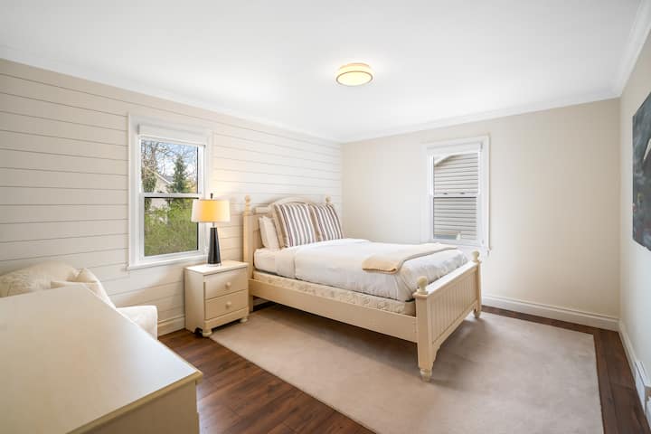 Guest bedroom with Queen bed, clean linens, dresser, roller shades.