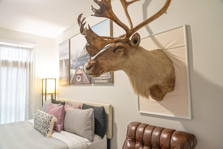 在这间时尚的卧室中放松身心，配备豪华特大号床、舒适的扶手椅和坐骑式驯鹿头部，增添了一丝乡村风情。 大窗户提供自然光线和城市风光。