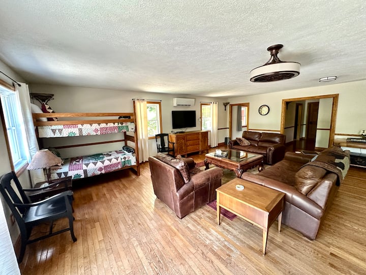 Upstairs living room-leather furniture, lots of seating, chairs and table, twin/twin bunk bed, TV, gaming console, keyboard.