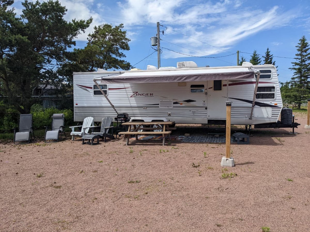 Camper with patio chairs and picnic table