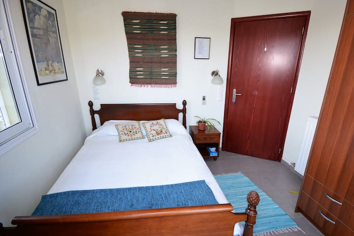 Спалнята „Гнездото на сокола“ в основната къща.  Уютно място за двама, с антично ръчно издялано легло от клен, големи гардероби и отделен балкон с изглед към долината на река Тифлос и южните планини.