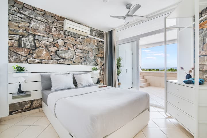 Bedroom Oasis: Contemporary elegance with stone accents and ocean views awaits your relaxation.