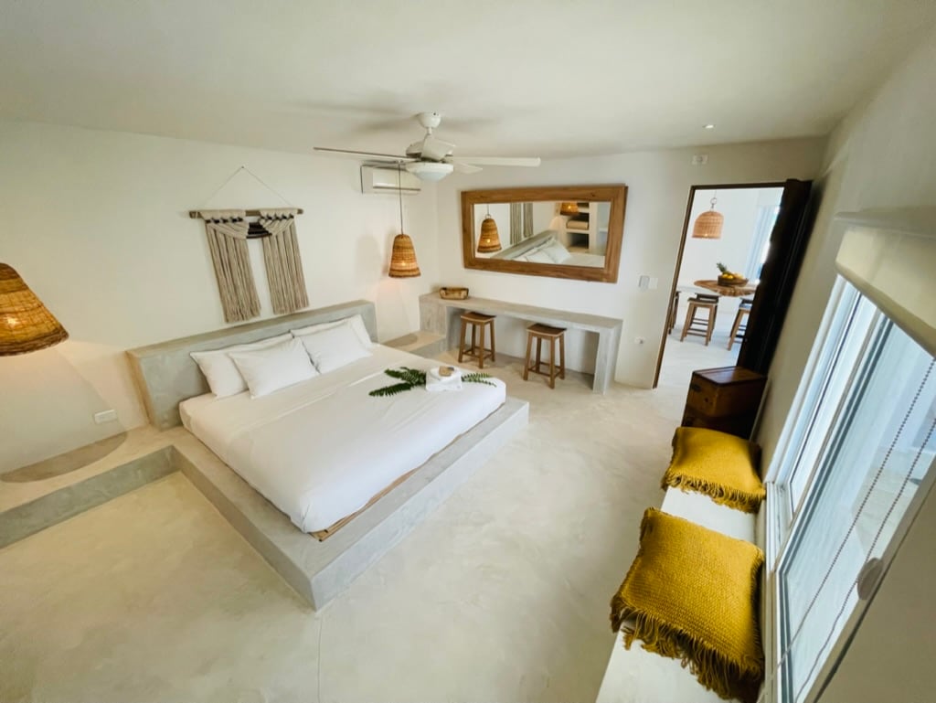 El dormitorio de Casa Almea invita al descanso con su estilo boho-fino y tonos naturales. Una cama king, luz suave y detalles artesanales crean un ambiente relajante con vista al mar y total privacidad.