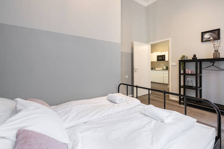 Espace de couchage confortable au design moderne et minimaliste, baigné d'une lumière naturelle douce provenant de grandes fenêtres.