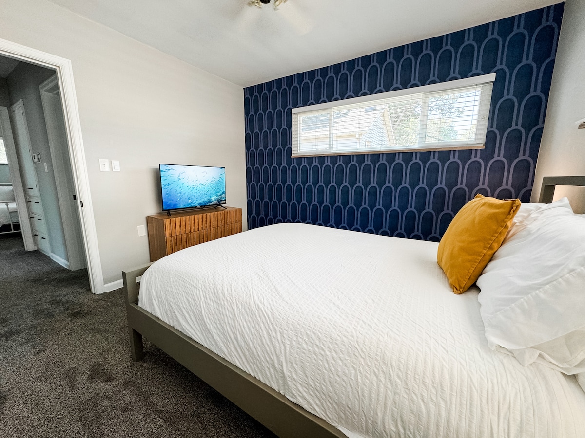 נוחו בקלות בחדר שינה מעוצב עם מיטת קווין סייז, קיר מודגש מודרני ואור טבעי לשינה מרגיעה.