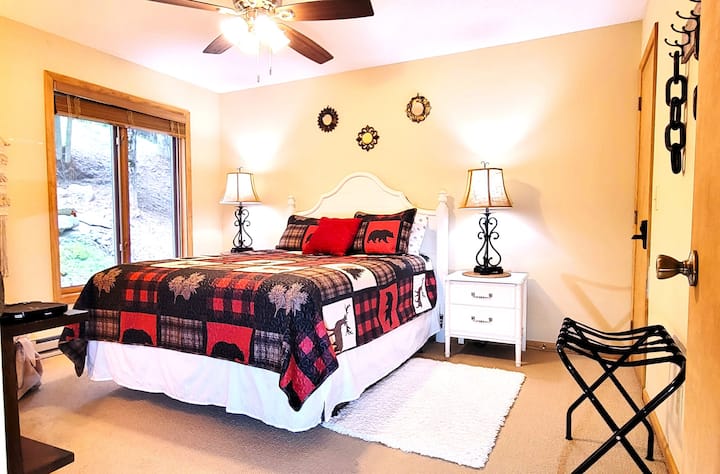 Priestranná manželská posteľ Queen s pohodlným matracom, televízorom, vedľa priestrannej kúpeľne s vaňou a veľkým oknom.