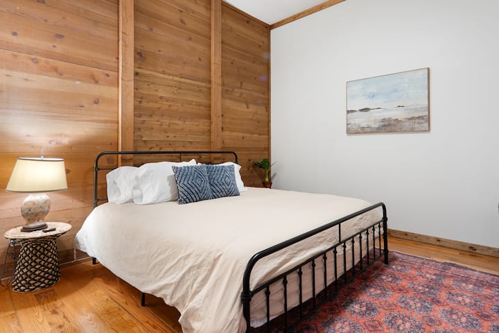 This king bedroom is on the lower floor, located in the hallway at the bottom of the stairs. There is an armoire for your clothing and a full bathroom with shower located just outside of this bedroom.