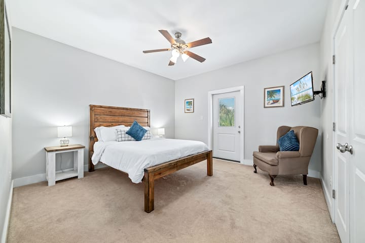 Оваа мирна спална соба има рустикален дрвен кревет, свежа бела постелнина и смирувачка неутрална палета. Удобна фотелја со перници инспирирани од океанот го надополнува пристапот до приватниот поплочен двор, додека телевизорот монтиран на ѕид обезбедува забава во секое време!