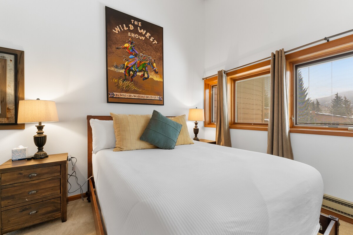 Chumba cha kulala cha mgeni cha ghorofa kilicho na kitanda cha malkia, kitanda cha siku mbili na televisheni iliyowekwa. 